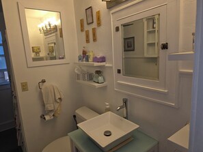A bathroom with a white sink, a mirror, a towel rack, and a shelf with toiletries. - Perfect 2-bedroom house, walk downtown Appleton or Packer stadium 30 min drive (Appleton)
