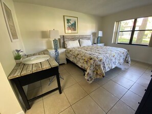 A bedroom with a bed, bedside tables, a nightstand, a window, and a painting on the wall. - 2-bedroom in Bradenton close to IMG and beach . (Bradenton)