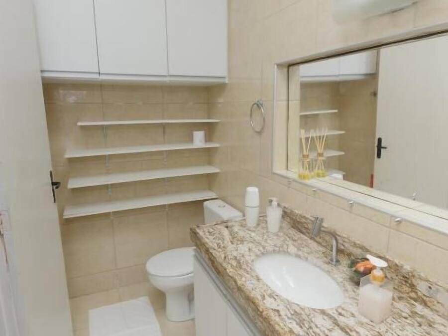 A bathroom with a white toilet, a sink with a marble countertop, and a mirror above the sink.