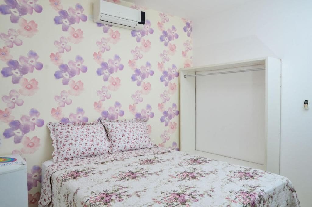 Une chambre à coucher avec un lit, un papier peint à motifs floraux et une armoire blanche.