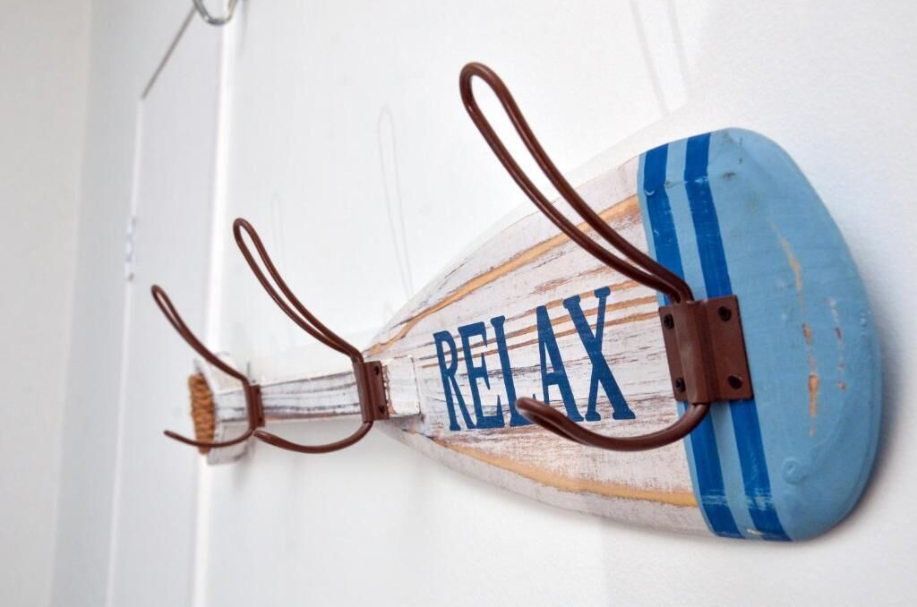 Un gancho de pared con asa de madera y diseño azul y blanco a rayas.
