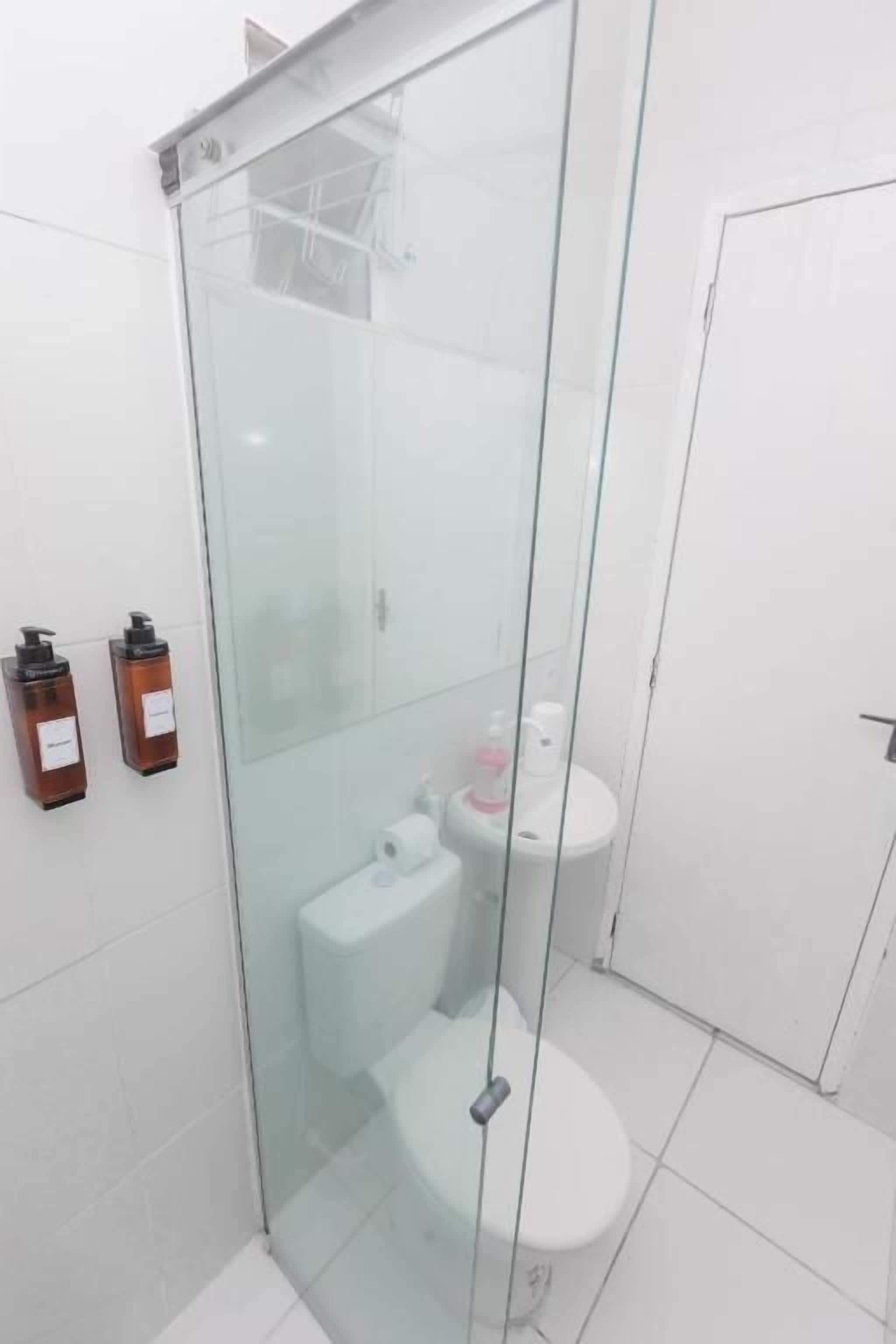 A modern bathroom with a glass-enclosed shower, a toilet, and a sink.