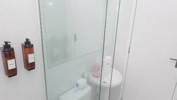 A modern bathroom with a glass-enclosed shower, a toilet, and a sink.