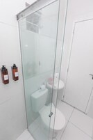 Un baño moderno con ducha envuelta en vidrio, inodoro y lavabo.