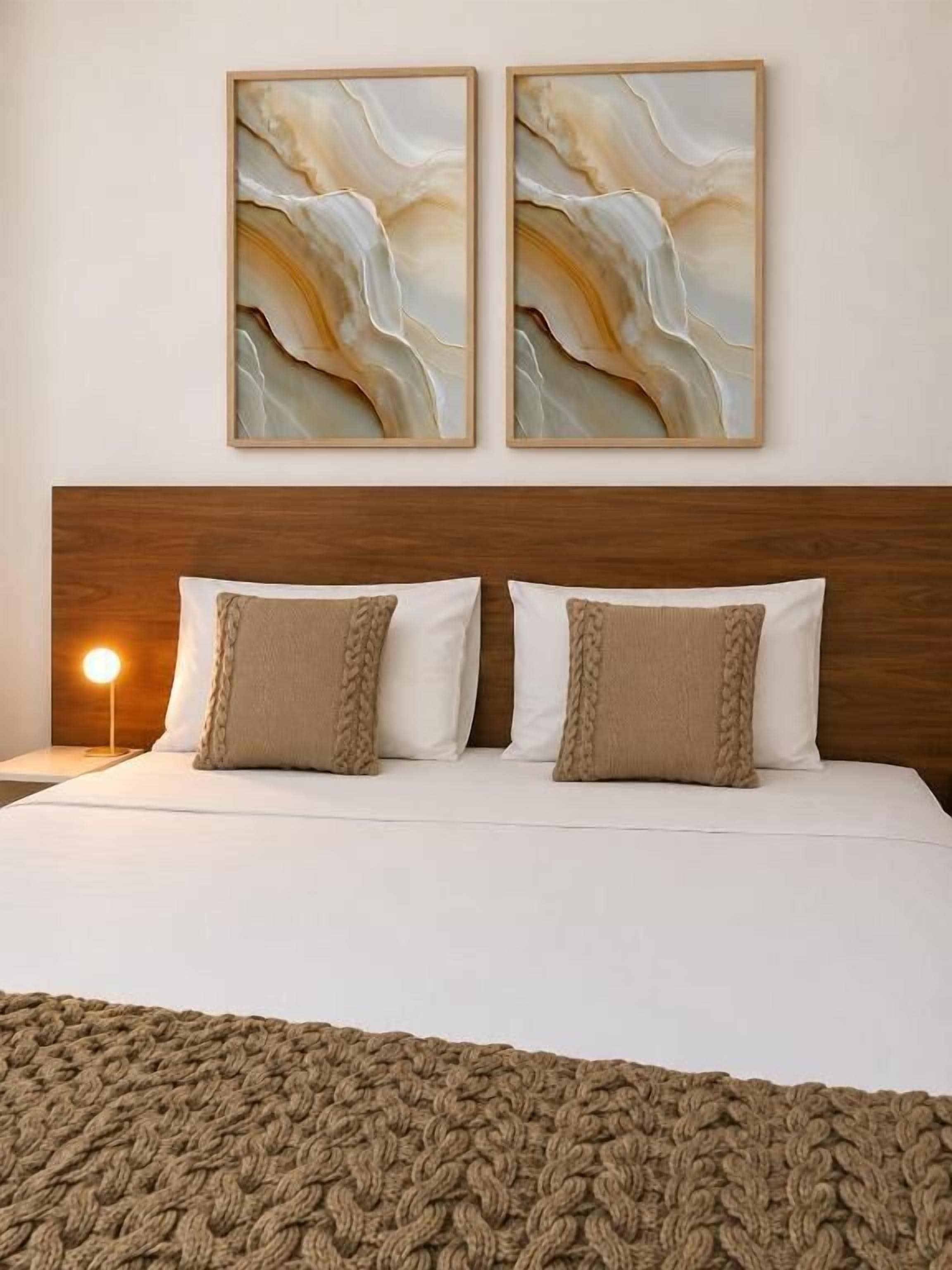 Een bed met een houten hoofdbord, twee kussens en een gebreide plaid.