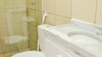 Baño con inodoro, lavamanos y zona de ducha.