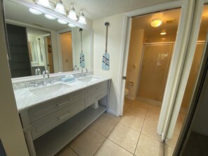 Une salle de bain avec un meuble-lavabo à deux vasques, un grand miroir et un espace douche.