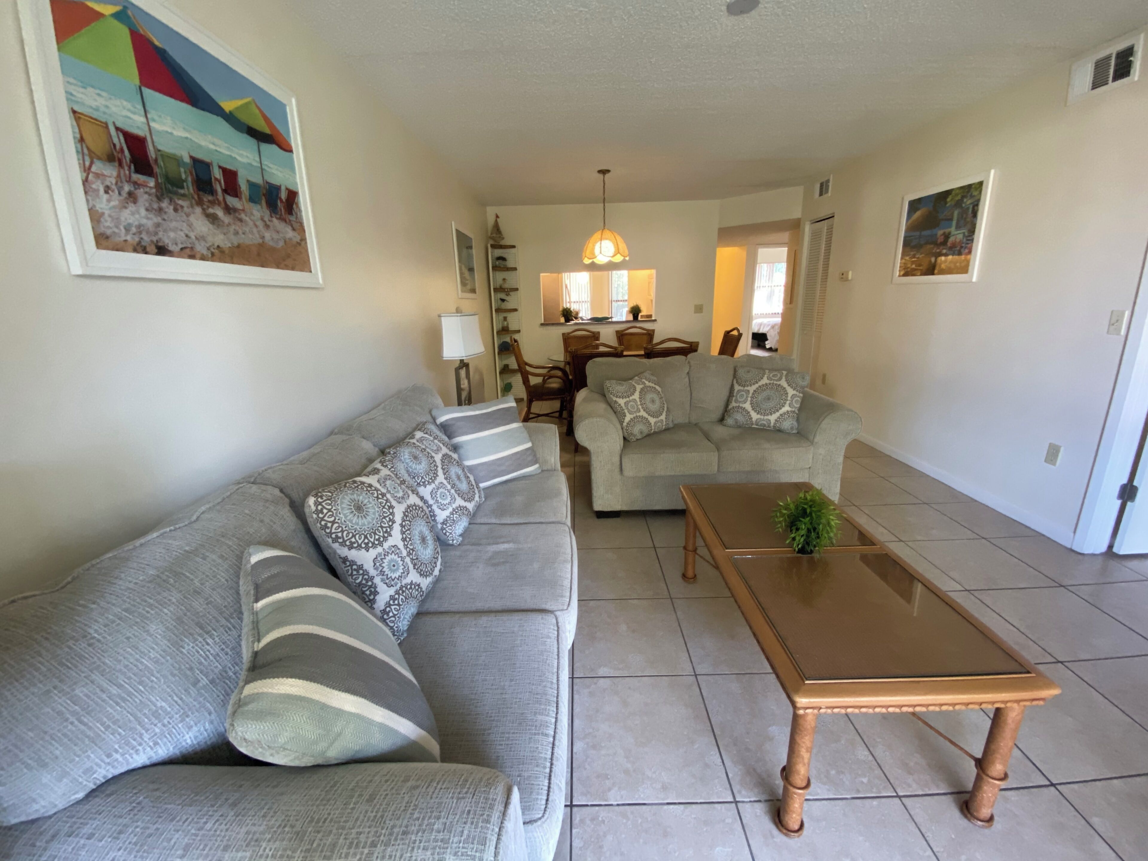 A living room with a sofa, a coffee table, and a dining area in the background.