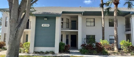 A two-story residential building with a green door and a balcony.
