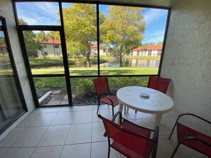 Une pièce avec une grande fenêtre, une table ronde et des chaises rouges.