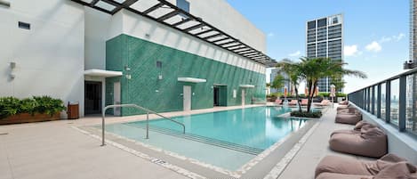 Zona de piscina en la azotea con vista despejada del horizonte urbano, incluyendo un edificio alto.