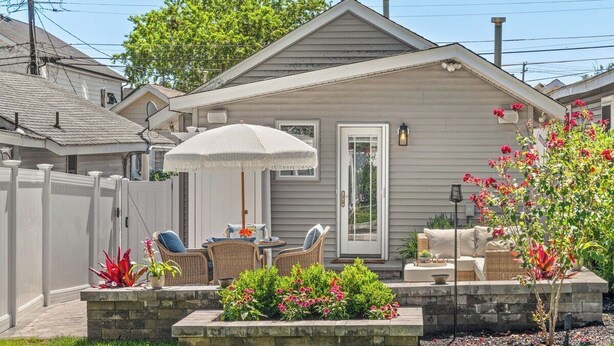A residential house with a patio area featuring outdoor furniture and a garden.
