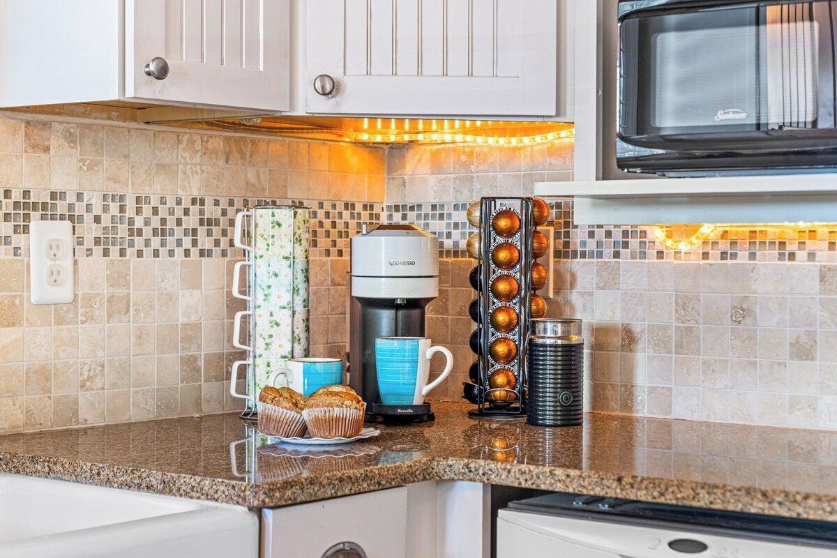 Una cocina con cafetera, molde para muffins y molinillo de café sobre la encimera.