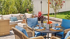 An outdoor seating area with wicker furniture, a round table, and a decorative umbrella.