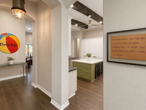 A modern kitchen with a central island, white cabinetry, and a ceiling fan. - Settle in and stay awhile at this beautifully furnished luxury home! (New Braunfels)