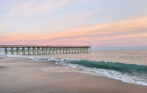 Eine Pier, die sich ins Meer erstreckt, während Wellen an das Ufer schlagen.