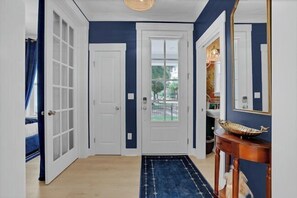 Ein Flur mit einer blauen Tür, einer weißen Tür und einem Spiegel an der Wand.