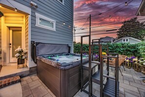 A hot tub with a wooden deck and a pergola, surrounded by outdoor furniture and plants. - The Savoy | Art Deco Luxury + Hot Tub (Wilmington)