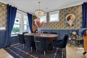 A dining area with a round table, chairs, and a chandelier. - The Savoy | Art Deco Luxury + Hot Tub (Wilmington)