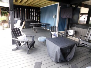 Eine Terrasse im Freien mit überdachter Sitzgruppe, inklusive Tisch und Stühlen sowie einem Grill.