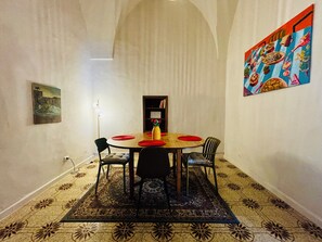 Zona pranzo con tavolo rotondo, sedie, tappeto e libreria.
