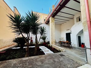 Un cortile con piante in vaso, un tavolo e sedie.