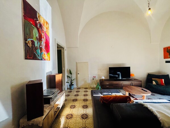 Un soggiorno con televisione, divano e un quadro appeso al muro.