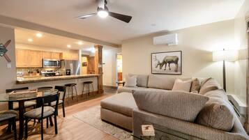 A modern living room with a sofa, a glass coffee table, and a dining area with chairs and a table.