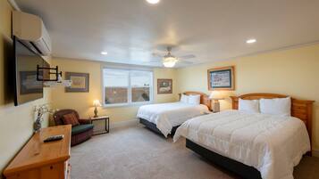A bedroom with two beds, a ceiling fan, a window, and a bedside table with a lamp.