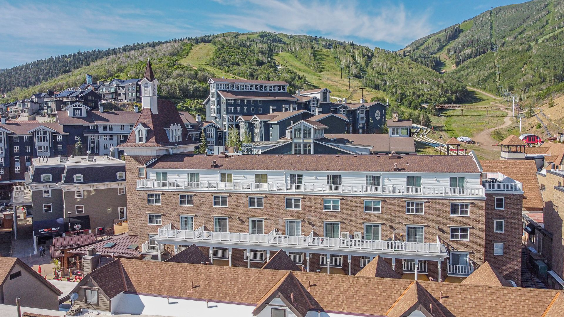 A multi-story building with a prominent tower, surrounded by other residential buildings, set against a backdrop of green hills.