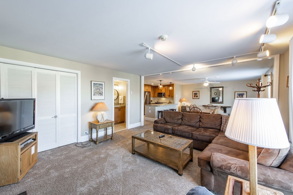 A living room with a television, sofa, coffee table, and lamp.