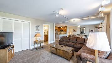 A living room with a television, sofa, coffee table, and lamp.
