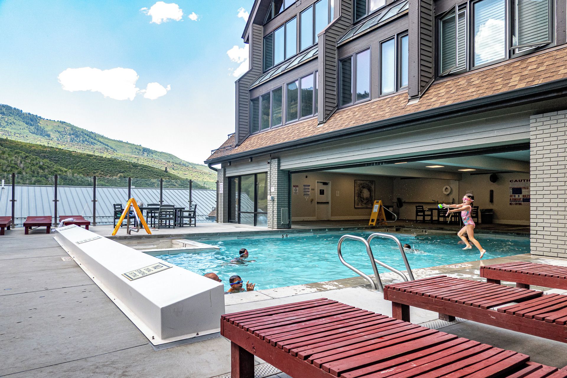 Un espace piscine comprenant une piscine, un plongeoir et des chaises longues.