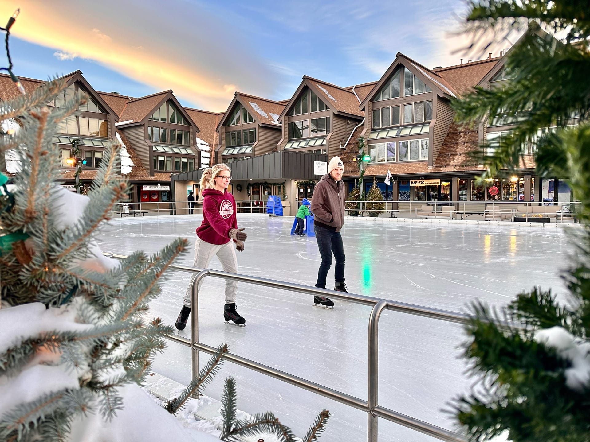 Une patinoire en plein air, entourée de bâtiments au style architectural moderne et dotée d’une barrière métallique.