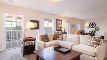 A living room with a sectional sofa, a coffee table, a side table with books, and a lamp.