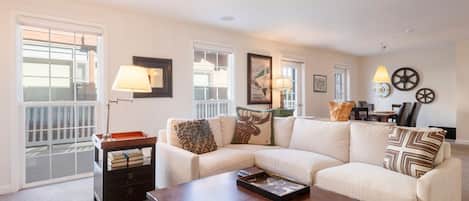 A living room with a sectional sofa, a coffee table, a side table with books, and a lamp.