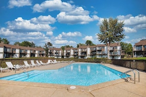 A rectangular swimming pool with a tiled deck, surrounded by lounge chairs and a wooden fence. - North Shore Retreat | Beachfront • Pool • Walkable (South Haven)