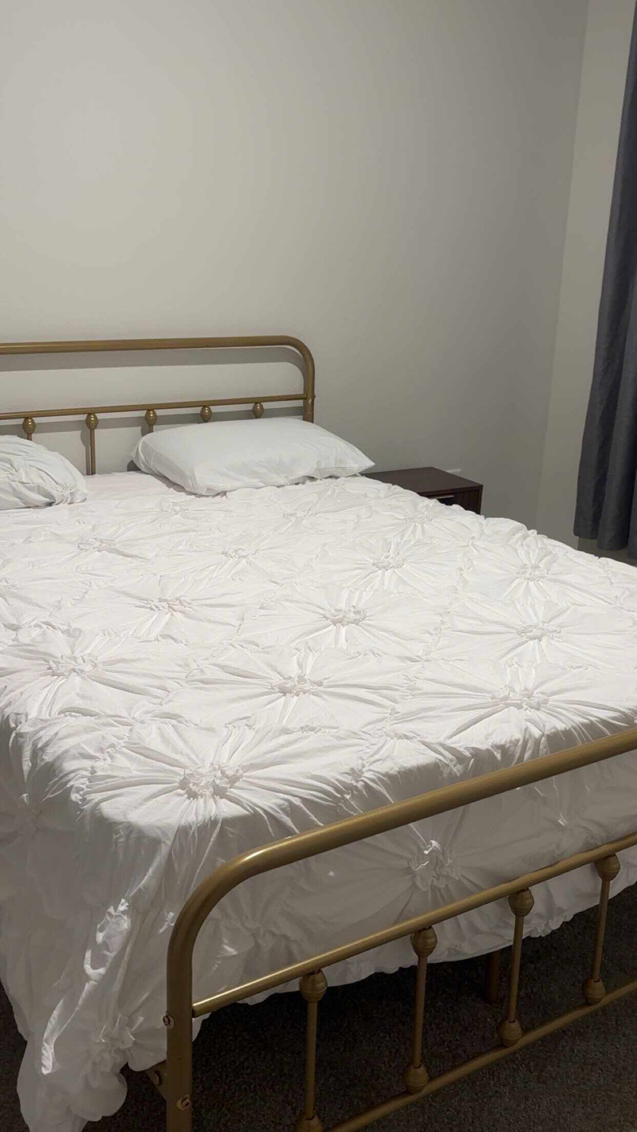 Un lit simple avec un cadre en métal et du linge de lit blanc.