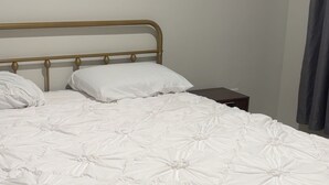 Un letto singolo con struttura in metallo e biancheria da letto bianca.