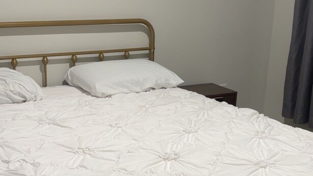 A single bed with a metal frame and white bedding.