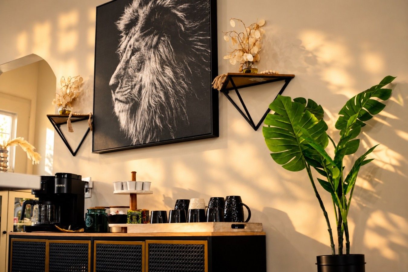 Eine wandmontierte Kaffeemaschine, ein gerahmtes Foto und ein Blumentopf.