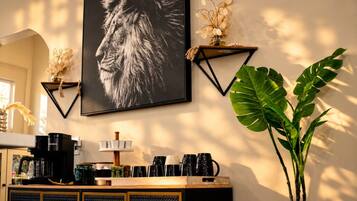 Eine wandmontierte Kaffeemaschine, ein gerahmtes Foto und ein Blumentopf.
