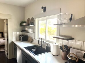 A modern kitchen with a sink, microwave, and various utensils. - The Moody Modern*2KING beds*2bath*Walkable* (Albany)