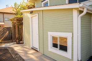 A residential building with a front door, a small window, and a wooden fence.