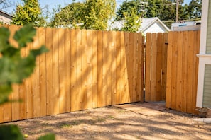 A wooden fence with a gate, a paved driveway, and a house in the background. - The Moody Modern*2KING beds*2bath*Walkable* (Albany)