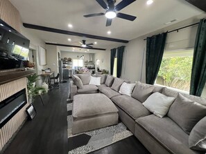 A modern living room with a sectional sofa, a flat-screen TV, and a ceiling fan. - The Moody Modern*2KING beds*2bath*Walkable* (Albany)