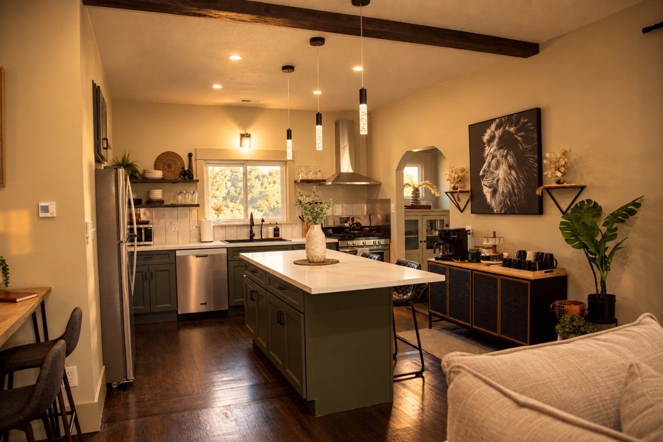 A modern kitchen with a central island, wooden flooring, and pendant lighting.