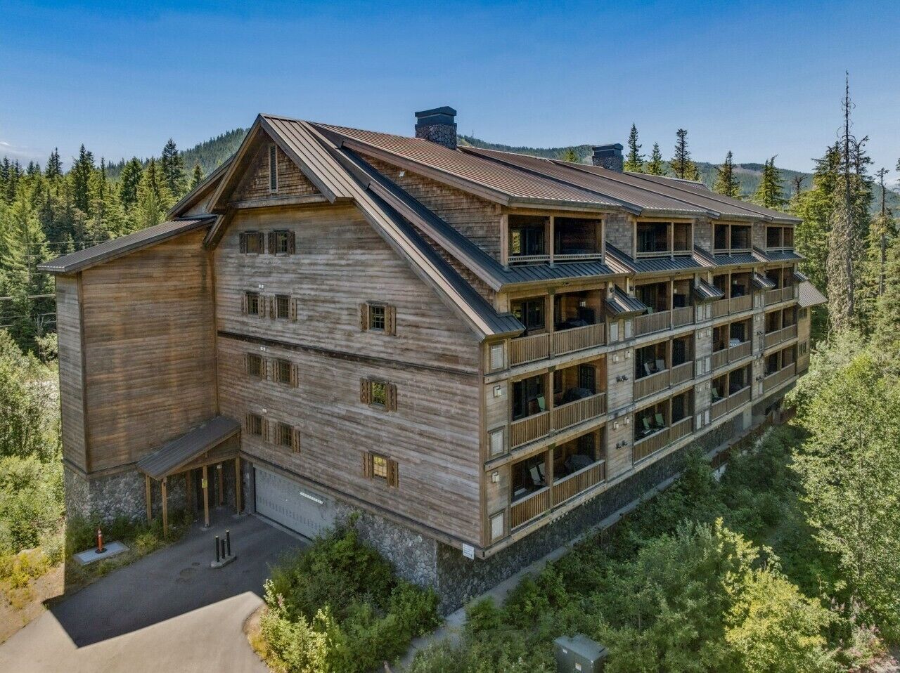 Un chalet en bois à plusieurs étages, doté de balcons et surplombant un paysage montagneux.
