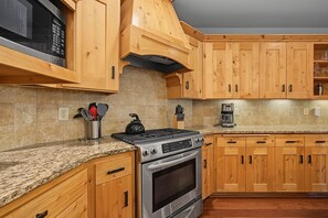 Eine Küche mit Holzschränken, einem Edelstahlherd, Granit Arbeitsplatten und einer Kaffeemaschine.