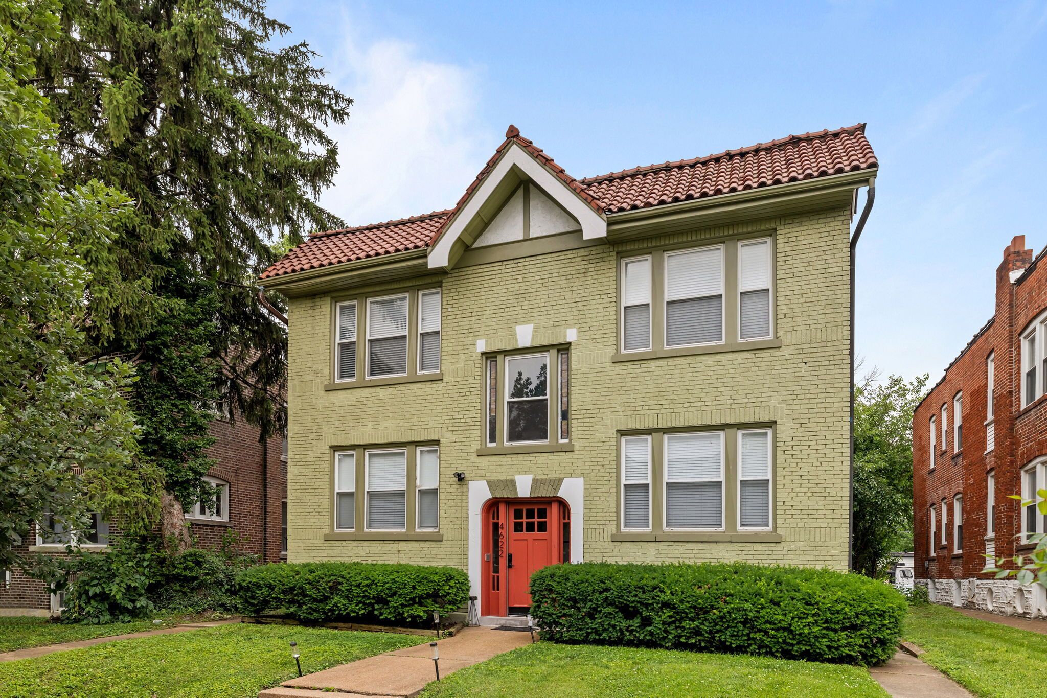 A two-story building with a red door, multiple windows, and a brick facade.
